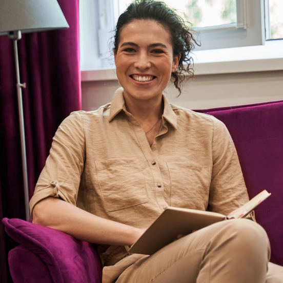 Woman smiling while sitting in a chair reading a book